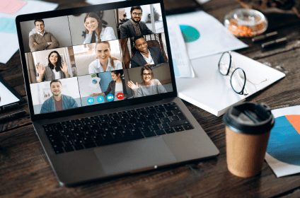 photo of a laptop with a business video conference going on. 9 people appear with their video cams